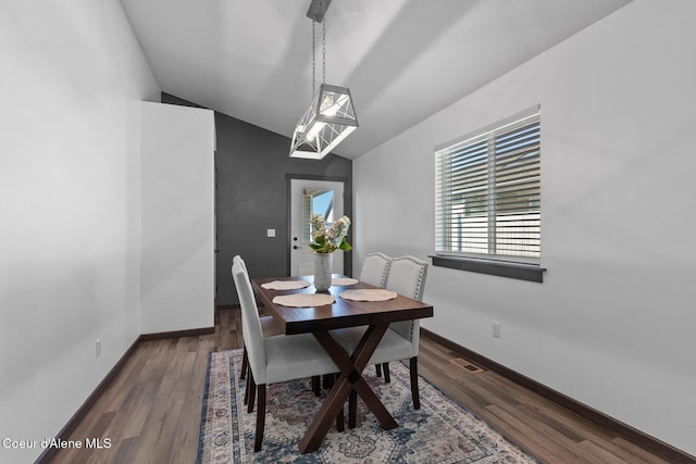 dining area with dark wood-type flooring and vaulted ceiling