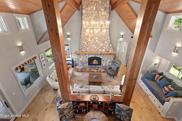 living room with high vaulted ceiling, wooden ceiling, a stone fireplace, and light wood-type flooring