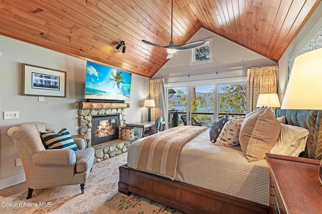 bedroom with lofted ceiling, wood-type flooring, a stone fireplace, and wooden ceiling