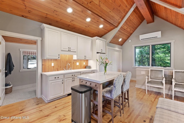 kitchen with white cabinets, white refrigerator, a wall mounted AC, and light hardwood / wood-style flooring