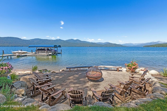 property view of water featuring a mountain view, a fire pit, and a boat dock