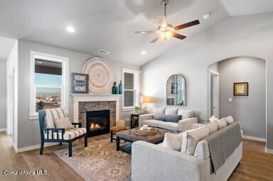 living room featuring ceiling fan, lofted ceiling, hardwood / wood-style flooring, and a stone fireplace