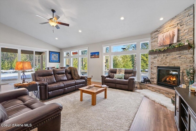 living room featuring high vaulted ceiling, a stone fireplace, recessed lighting, wood finished floors, and baseboards