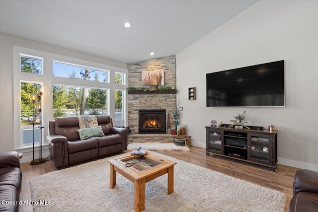 living room featuring a stone fireplace, wood finished floors, and baseboards