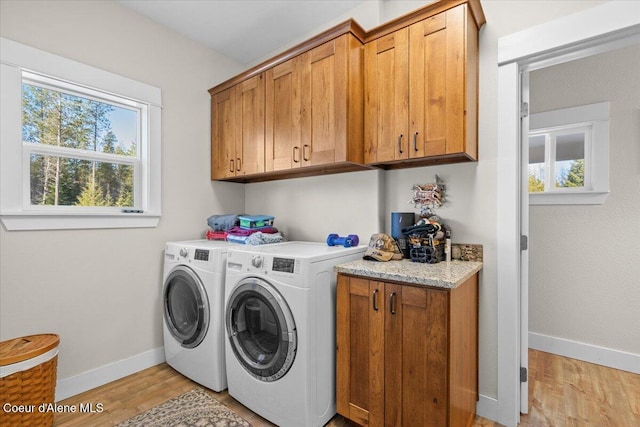 clothes washing area featuring baseboards, separate washer and dryer, cabinet space, and light wood-style floors