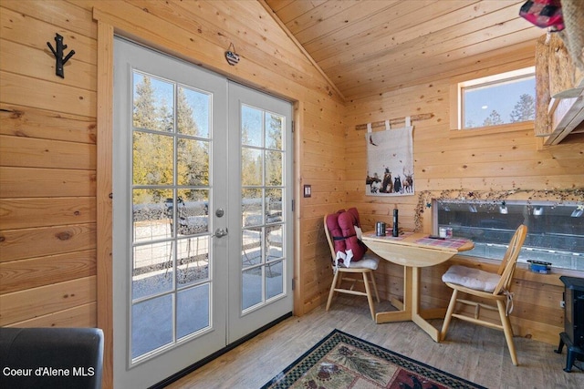 dining room featuring french doors, vaulted ceiling, wooden walls, wood finished floors, and wooden ceiling