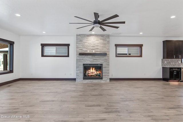 unfurnished living room with a fireplace, light hardwood / wood-style floors, plenty of natural light, and ceiling fan