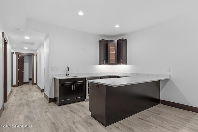 kitchen with wine cooler, sink, kitchen peninsula, light wood-type flooring, and a breakfast bar