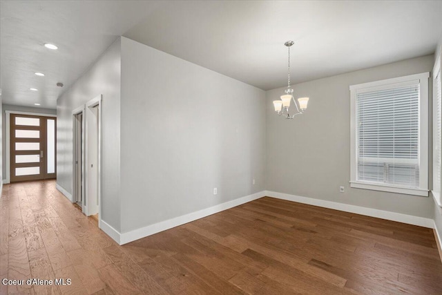 unfurnished room featuring a chandelier and hardwood / wood-style flooring