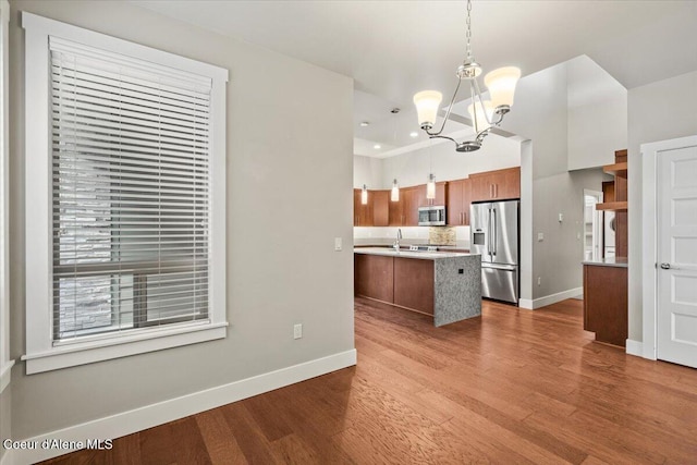 kitchen featuring an inviting chandelier, stainless steel appliances, wood-type flooring, hanging light fixtures, and a center island