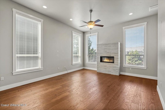 unfurnished living room with ceiling fan, hardwood / wood-style flooring, and a tiled fireplace