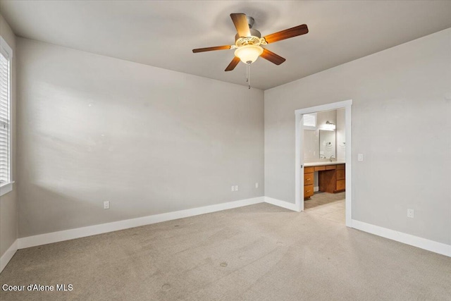 interior space with ceiling fan, light carpet, and ensuite bath