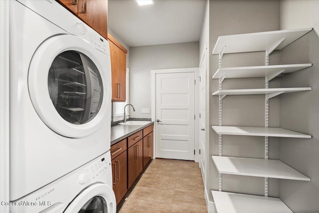 laundry room with cabinets, light tile patterned floors, sink, and stacked washer and dryer