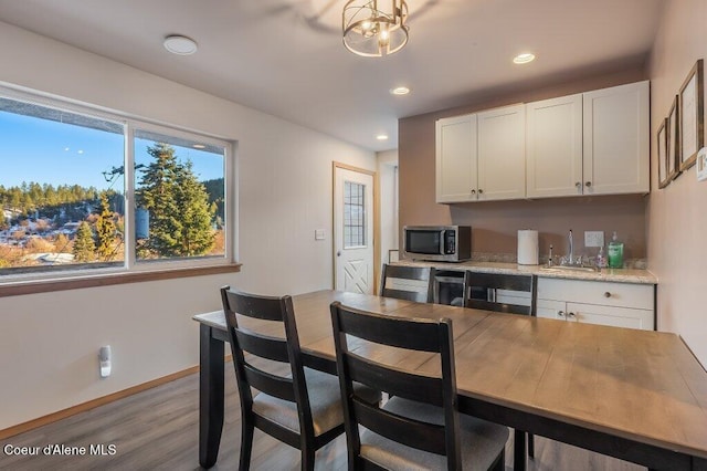 kitchen with light hardwood / wood-style floors, sink, light stone counters, and white cabinets