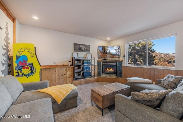 carpeted living room featuring a fireplace and wooden walls