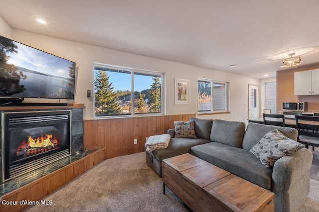 carpeted living room with a tile fireplace and wooden walls