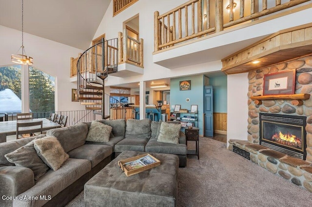 carpeted living room featuring a notable chandelier, a towering ceiling, and a stone fireplace