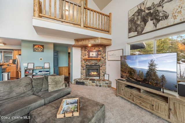 carpeted living room with a stone fireplace and a high ceiling