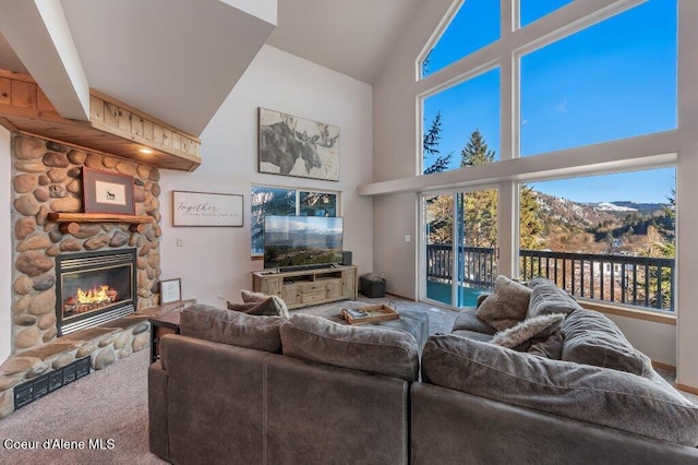 living room with vaulted ceiling, a stone fireplace, and carpet