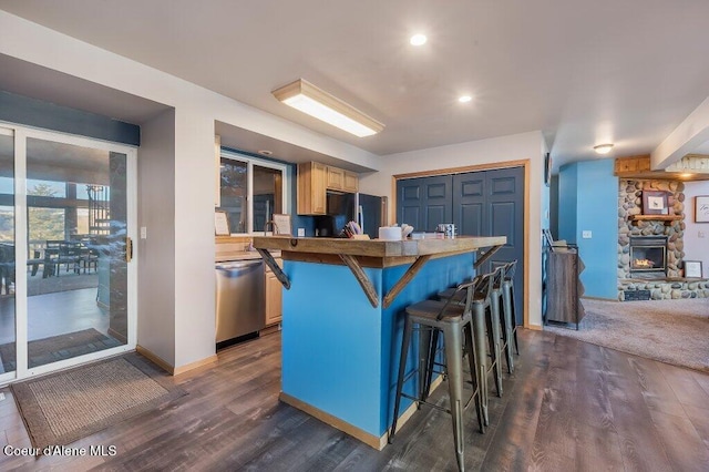 kitchen with a kitchen bar, black refrigerator, dishwasher, and dark wood-type flooring