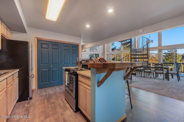 kitchen with hardwood / wood-style flooring, a kitchen breakfast bar, a wealth of natural light, and stainless steel appliances