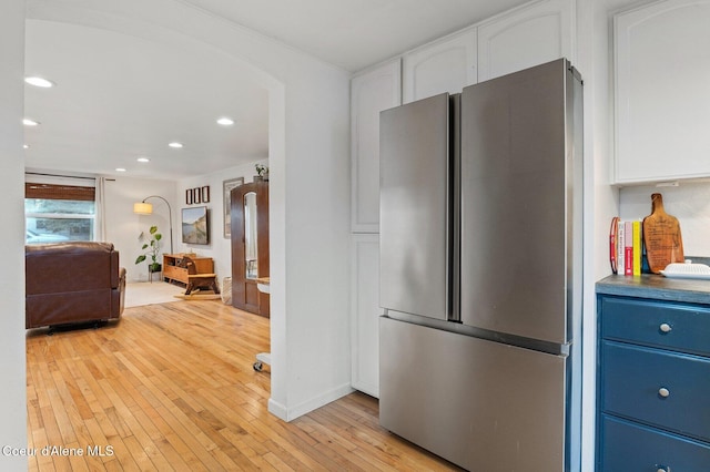 kitchen featuring light wood-type flooring, blue cabinetry, white cabinets, and stainless steel fridge