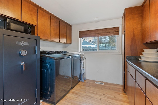 laundry area with light wood-type flooring and washing machine and clothes dryer