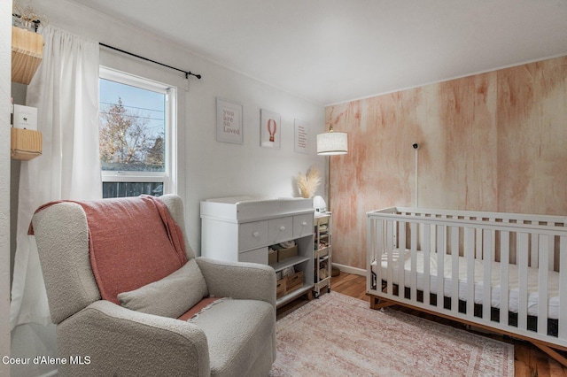 bedroom featuring light wood-type flooring and a crib