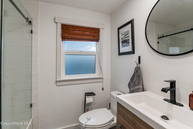 bathroom with vanity, toilet, and tiled shower