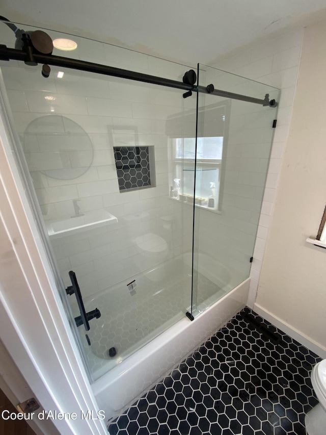 bathroom with tile patterned floors, toilet, and a shower with door