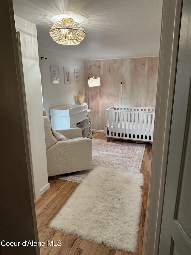 bedroom with hardwood / wood-style floors and a crib