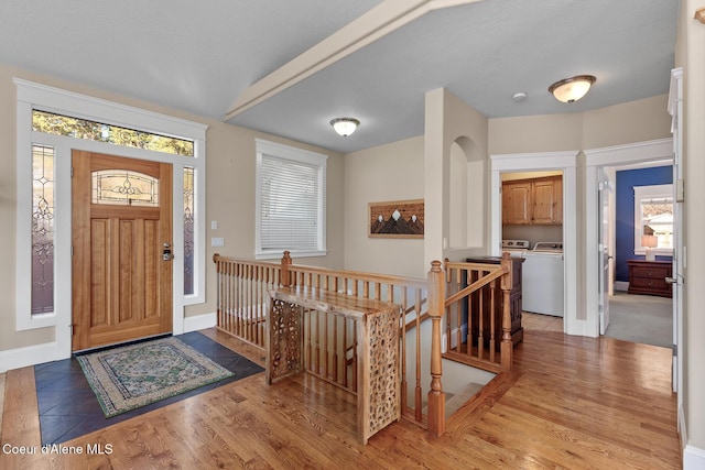 foyer entrance with washing machine and dryer and light hardwood / wood-style floors