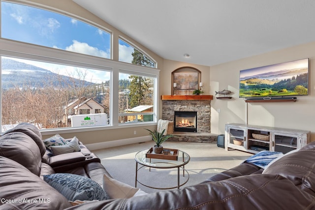 living room featuring vaulted ceiling, light colored carpet, a mountain view, and a stone fireplace