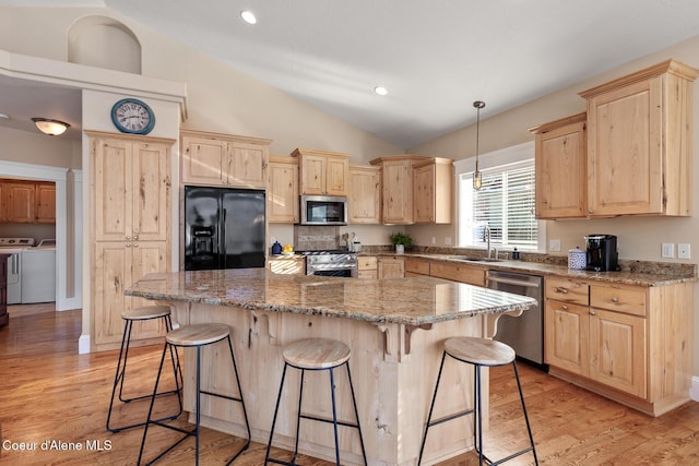 kitchen with a breakfast bar area, light stone counters, separate washer and dryer, and stainless steel appliances