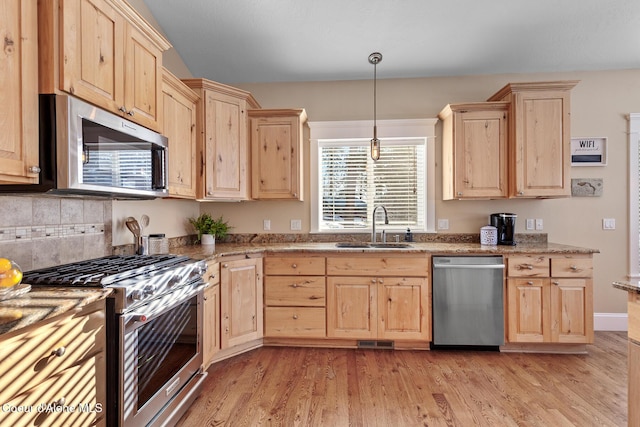 kitchen featuring hanging light fixtures, light brown cabinetry, sink, and stainless steel appliances