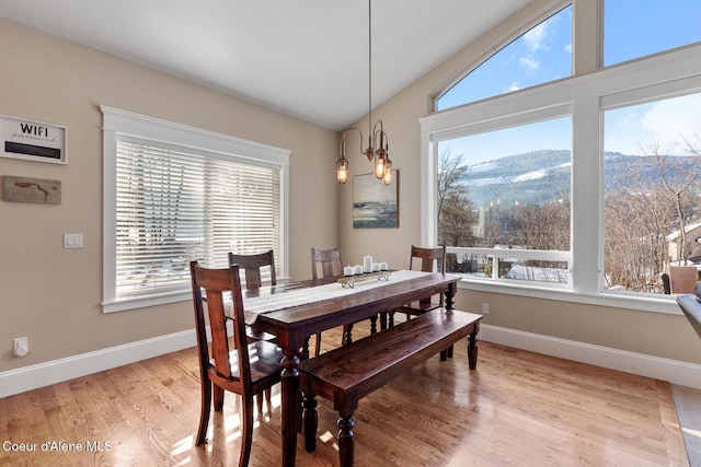 dining area featuring vaulted ceiling, an inviting chandelier, a wealth of natural light, and a mountain view