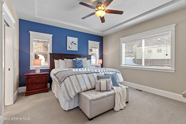 carpeted bedroom featuring ceiling fan and a tray ceiling