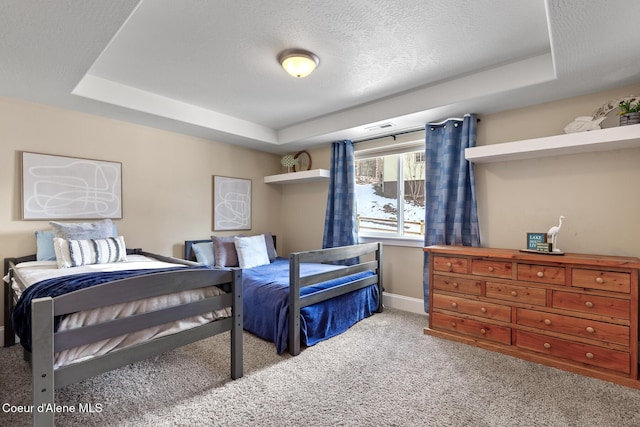 carpeted bedroom featuring a raised ceiling and a textured ceiling