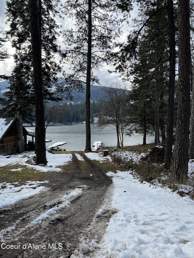 snowy yard featuring a water and mountain view