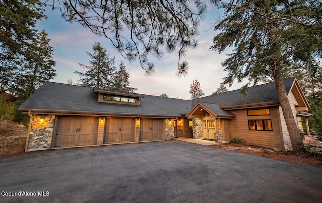 view of front of home with an attached garage, stone siding, and aphalt driveway