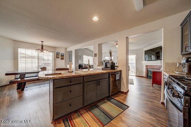 kitchen featuring black dishwasher, a healthy amount of sunlight, gas stove, and light stone counters