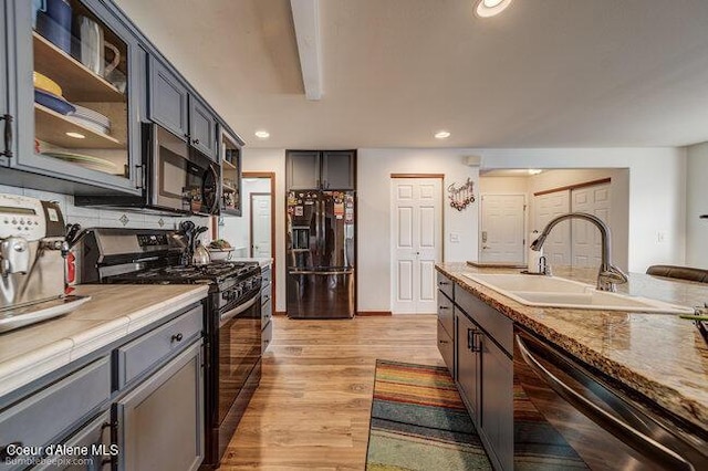 kitchen with sink, black appliances, and light wood-type flooring