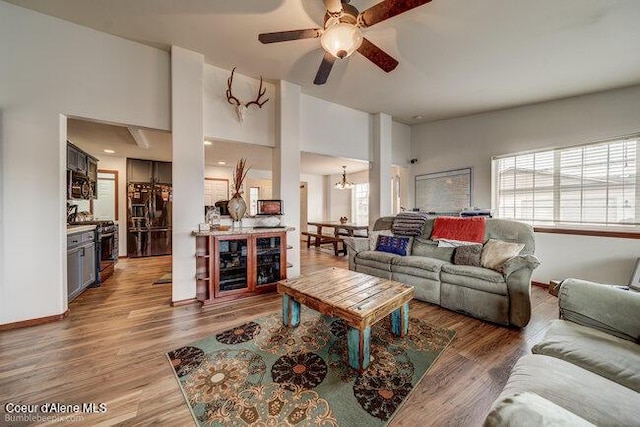 living room with wood-type flooring and ceiling fan with notable chandelier