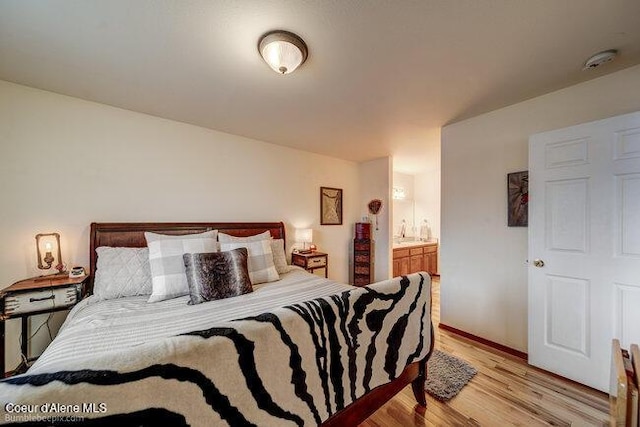 bedroom featuring ensuite bathroom and light hardwood / wood-style floors