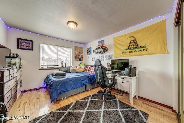 bedroom with a textured ceiling and light hardwood / wood-style floors