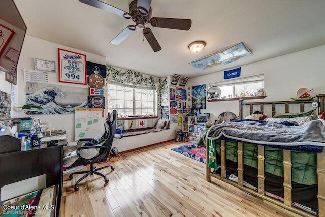 bedroom featuring ceiling fan, multiple windows, and hardwood / wood-style floors