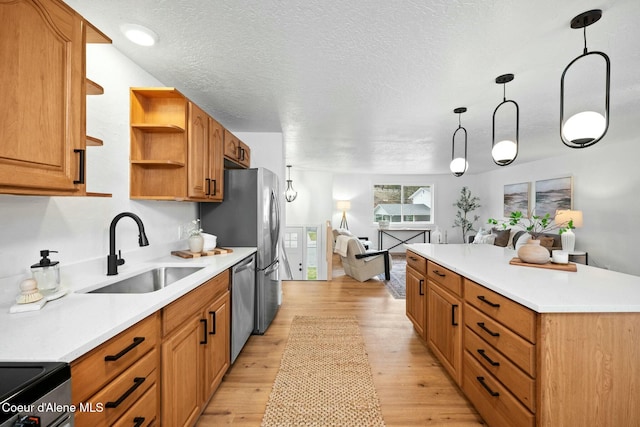 kitchen featuring stainless steel appliances, hanging light fixtures, a kitchen island, light hardwood / wood-style flooring, and sink