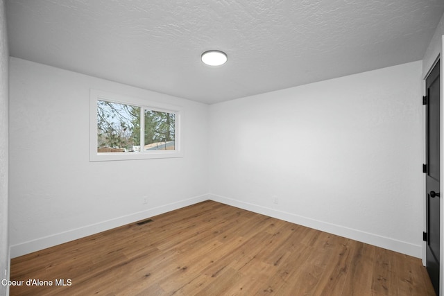 spare room featuring hardwood / wood-style flooring and a textured ceiling