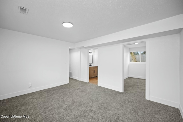 interior space with connected bathroom, a textured ceiling, and dark colored carpet