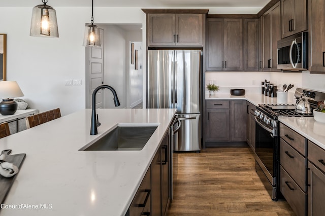 kitchen featuring pendant lighting, sink, dark brown cabinetry, stainless steel appliances, and dark hardwood / wood-style flooring